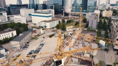 Drone shot of yellow crane over construction site in housing estate in the center of Warsaw Poland with modern skyscrapers in the bakground. Horizontal. High quality 4k footage