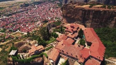 Etkileyici ortodoks dağ manastırları. Meteora Manastırı 'nın yüksek kaya oluşumu üzerine kurulmuş güzel bir manzarası var. Mavi gökyüzü. Arka planda Yunan şehri var. Yüksek kalite 4k görüntü