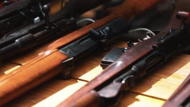Ahşap bir masanın üzerinde duran temiz silahlar. Yakın çekim yavaş çekim perspektifinden görülen çeşitli kahverengi ve siyah tüfekler. - Evet. Yüksek kalite 4k görüntü