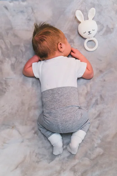 刚出生的男婴 棕色的秀发 带着毛绒绒的白兔玩具睡在家里的毛毯上 高质量的照片 — 图库照片
