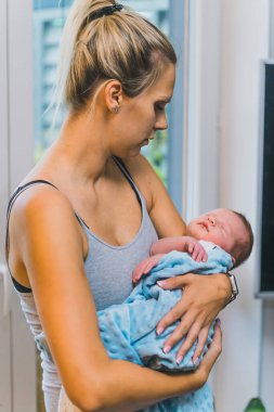 Beyaz, evli bir kadın yeni doğmuş bebeğini battaniyeye sarıp uyutuyor. 
