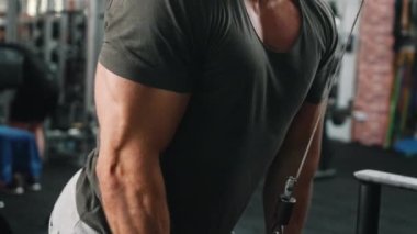 Kas beyazı, tişörtlü, düz çekme makineli bir adam. Göğüs ve pazılara yakın durun. Güç kaldırma. Fitness. Yatay olarak. Yüksek kalite 4k görüntü