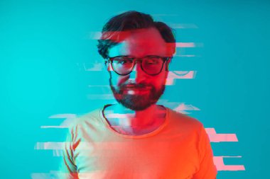 30 yaşındaki beyaz sakallı, büyük gözlüklü ve turuncu tişörtlü bir adamın yakın çekim çekimlerinde kullanılan arıza efekti. Mavi arka plan. Özel fotoğraf efektleri. Yüksek kalite fotoğraf