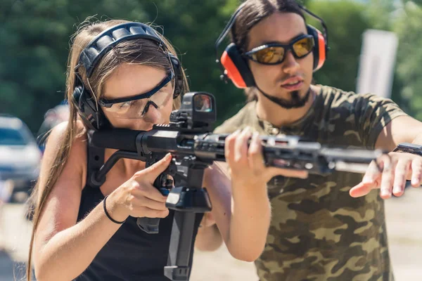 woman practicing target shooting with an instructor at the shooting range, medium closeup. High quality photo