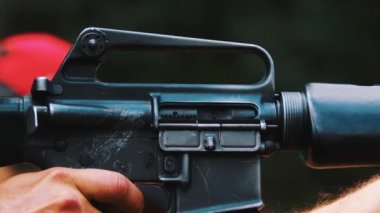 Açık hava atış poligonunun kısa yavaş çekim klibi. Siyah bir tüfeğin yakın çekim görüntüsü ve altın mermi kovanı. Alışılmadık bir hobi. Yüksek kalite 4k görüntü
