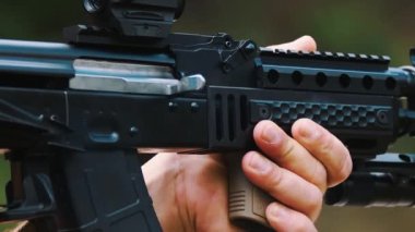 Siyah tüfekten fırlayan altın kovanın yavaş çekim klipsi. Kafkasyalı birinin elleri ateş etme makinesini tutuyor. Alışılmadık bir hobi. Yüksek kalite 4k görüntü