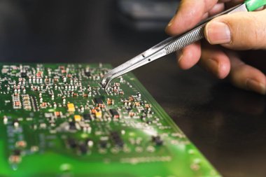PCB baskılı devre kartına cımbızla elektriksel bileşenler monte eden tanınamaz haldeki birinin yakın çekim görüntüsü. Elektronik tamir. Kusursuz bir iş. Yatay çekim. Yüksek kalite fotoğraf