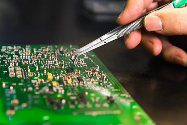 PCB baskılı devre kartına cımbızla elektriksel bileşenler monte eden tanınamaz haldeki birinin yakın çekim görüntüsü. Elektronik tamir. Kusursuz bir iş. Yatay çekim. Yüksek kalite fotoğraf
