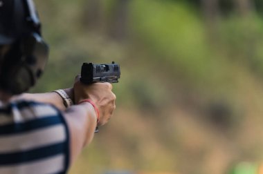 Atış poligonunda silahla atış talimi yapan bir adam. Orta mesafeden yakın plan bulanık. Yüksek kalite fotoğraf