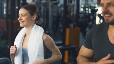 Genç bir kadın ve bir adam spor salonundaki koşu bandında koşuyor. Orta derecede yakın çekim. Yüksek kalite fotoğraf