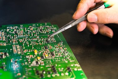 Baskılı devre kartının onarılması PCB 'nin cımbızla elektrik bileşenlerini elle monte etmesi. Tam onarım işi. Yatay olarak yakın çekim. Yüksek kalite fotoğraf