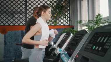 Modern spor salonunda koşu bandında koşan erkek ve kadın arkadaş. Grup çalışması. Fitness. Kardiyo. Yatay video. Yüksek kalite 4k görüntü