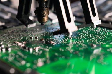 Basılı devre kartı PCB üzerinde çalışan SMD yüzey montaj cihazının yakın çekim görüntüsü. Elektrik bileşenleri monte ediliyor. Hassas teknoloji. Yatay