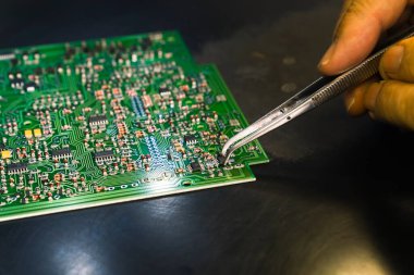 Yazılı çoklu kablo bağlantıları olan baskı devresi üzerinde elektronik parçaları ve mikro devreleri birleştiren teknisyenlerin profesyonel erkek eli. Elektronik İmalat Hizmetleri