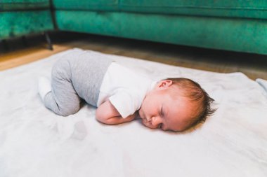 Yeni doğan bebek için uyku zamanı. Beyaz tişörtlü, gri eşofmanlı, göbeğinde uyuyan beyaz, sevimli bir oğlan çocuğu. Yüksek kalite fotoğraf