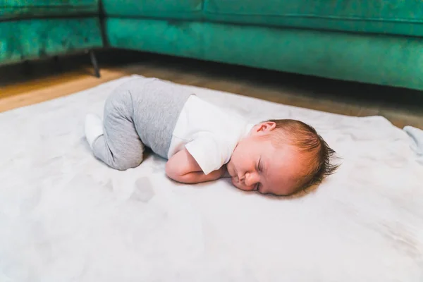 Childs innocence concept. Soft gray blanket for newborn babies being used by sleeping little caucasian baby boy in casual clothing. . High quality photo