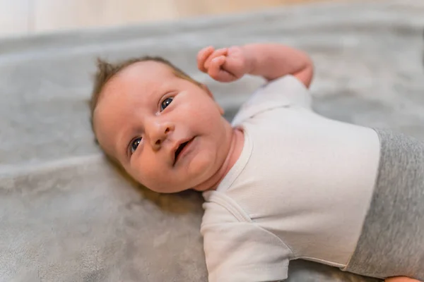 高加索新生男婴仰卧在地板上 手臂向上 好奇地看着相机 横向室内拍摄 高质量的照片 — 图库照片