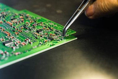 Otomatik makineler insan hassasiyetine karşı. El montaj konsepti. Profesyonel cımbız kullanarak PCB 'ye elektrik bileşenleri yerleştiren kadın bir mühendisin tanınamayan beyaz eli