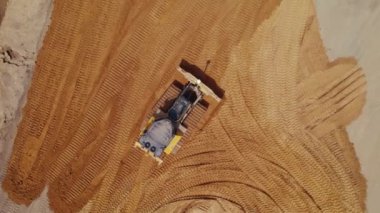 Yol inşaatı. İnşaat alanında yer değiştiren modern sarı buldozer, çok şeritli bir yolun toprak temelini hazırlıyor, zemini düzleştiriyor. Varşova, Polonya. Hava görüntüsü. Yüksek kalite 4k