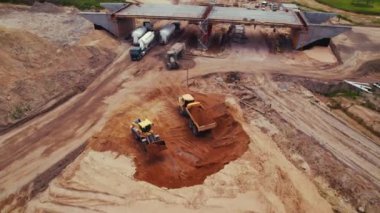 Toprak dolu bir bıçakla bir buldozer bir otoyol şantiyesine endüstriyel bir çöp kamyonu yüklüyor. Yer düzleştiriliyor. Varşova, Polonya. - Evet. Yüksek kalite 4k görüntü