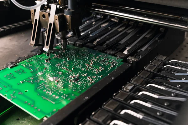 Close-up shot of SMD surface-mount device working on printed circuit board PCB. Assembling electrical components. Precision technology. Horizontal