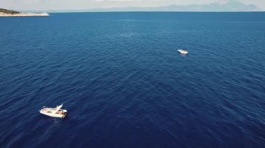 Yunanistan 'da tatiller. Sakin, koyu mavi deniz suyu, iki özel beyaz tekne ve turistler deniz kenarında eğleniyor ve güzel Mt. Athos. İHA görüntüsü. Yüksek kalite 4k görüntü