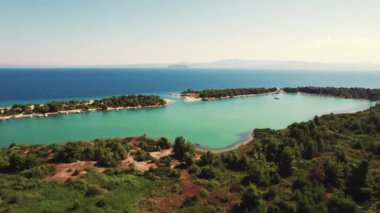 Glarokavos Sahili ve limanı kara tarafından görüldü. Turkuaz deniz suyuyla güzel limanın hava perspektifi daha sonra rengini koyu maviye çevirdi. Gökyüzü açık, hava güneşli. Başka bir ada