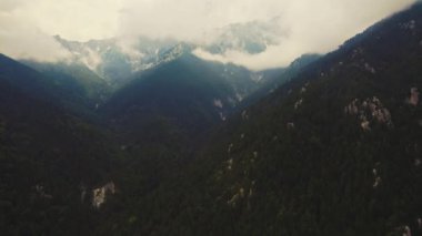 Görkemli Olimpos Dağı kuş bakışı perspektiften görülüyor. Sis ve bulutlar zirveyi kaplıyor. Doğal dokunulmamış çevre. Yüksek kalite 4k görüntü