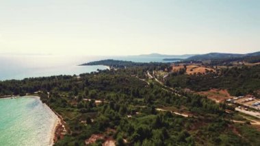 Yunanistan 'ın güzelliği ve çeşitliliği. Yavaş çekim hava perspektifi Glarokavos Sahili ve Limanı karadan görülüyor. Ağaçlarla dolu yeşil alan. Açık gökyüzü güneşli. Yüksek kalite 4k görüntü