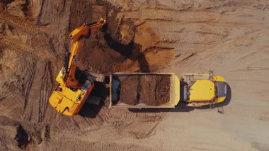 Uzun menzilli kazıcı Polonya 'nın Varşova kentindeki bir inşaat sahasındaki bir çöp kamyonuna toprak yüklüyor. Havadan görünüşlü. Yüksek kalite 4k görüntü