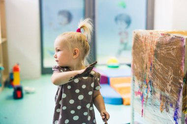 Sarışın ve Kafkasyalı küçük kız elleriyle çocuk odasında resim yapıyor. Arka planda bulanıklık var. Yüksek kalite fotoğraf