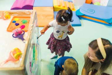 Anaokulunda selofanı boyayan çocuklar, arka planda anaokulu oyuncakları için yaratıcı aktiviteler. Yüksek kalite fotoğraf