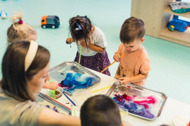 Anaokulunda öğretmenleriyle su boyası yapan sevimli anaokulu öğrencileri. Yüksek kalite fotoğraf