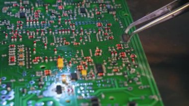 Elle yüzeye bağlanma teknolojisi montajında kullanılan çeşitli araçlar. Tanımlanamayan Kafkas mühendislerinin eli, mikroçipi basılı devre kartına yapıştırmak için cımbız kullanıyor. Yüksek kalite 4k