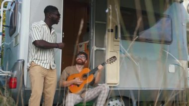 Arkadaşlığın güzelliği ve kampçı ile bağımsız seyahat. 30 'larında Afro-Amerikalı bir adam beyaz sakallı erkek arkadaşının üzerinde duruyor gitar çalıyor, ritme göre şarkı söylüyor. Minibüs. Yüksek