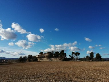 Güneşli kırsalda terk edilmiş bir ev. Mavi gökyüzü ve İspanya 'da beyaz bulutlar var.