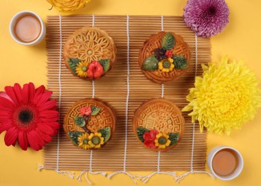 Renkli çiçek desenli ay pastası Sonbahar ortası Çin çayı küçük çay festivali papatyası kasımpatı anne çiçek sarı mor mor mor mor bambu yemek paspası sarı arka planda