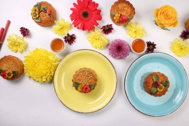 Renkli çiçek desenli ay pastası Sonbahar ortası Çin çayı küçük beyaz çay fincanı yemek çubukları tabak mavi menekşe kasesi, anne kırmızı papatya çiçeği beyaz arka planda.