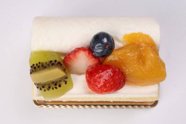 Beyaz arka planda Kivi çilekli mango meyveli kremalı pasta.