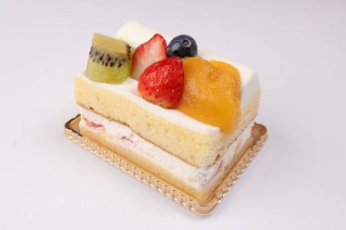 Beyaz arka planda Kivi çilekli mango meyveli kremalı pasta.