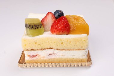 Beyaz arka planda Kivi çilekli mango meyveli kremalı pasta.