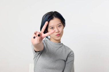 Genç ve çekici Asyalı Malezyalı kadın, beyaz arka planda yüz ifadesi pozu veriyor.