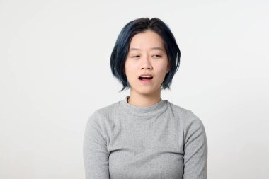 Genç ve çekici Asyalı Malezyalı kadın beyaz arka planda yüz ifadesi şeklinde bir ifade ortaya koyuyor.