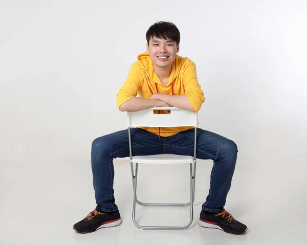 若いです良い見てアジアの中国のMalay男ポーズ顔ボディ式モード感情上のホワイトバックグランド座ってオン逆椅子ルック — ストック写真