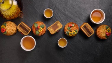 Renkli çiçek, ay pastası Çin sonbahar ortası, siyah kayrak taşı arka planda küçük beyaz seramik çay fincanı.