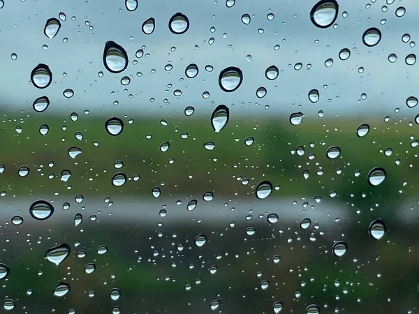 雨滴落在车窗玻璃绿色稻田背阴雨天 — 图库照片