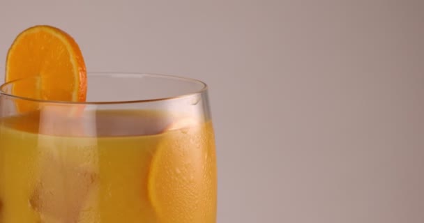 封闭式旋转玻璃杯 在玻璃杯边缘的橙子片上加入橙汁冰块霜 — 图库视频影像