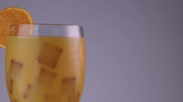 閉じた回転ガラスの縁にオレンジのガラスのスライス上にオレンジジュースキューブの霜でいっぱい — ストック動画