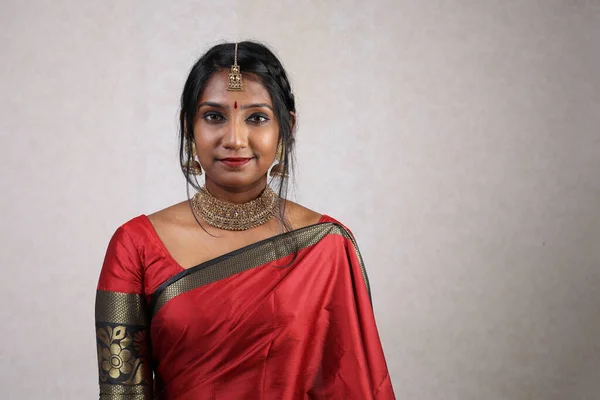 Indian woman wearing red orange traditional royal saree jewellery choker set necklace jhumka earring maang tikka waist chain stand pose look see smile mood expression at old rustic room background