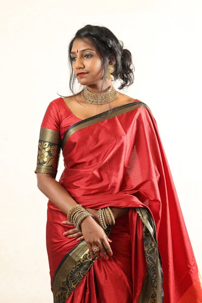 Indian woman wearing red orange traditional royal saree jewellery choker set necklace jhumka earring maang tikka waist chain stand pose look see smile mood expression at old rustic room background